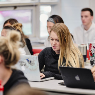 Students sitting in a classroom, laptops open in front of all of them.